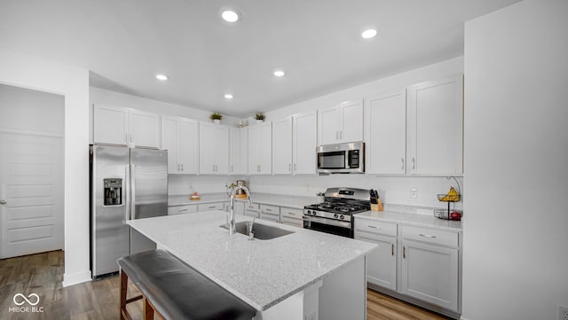 7226 Sayers Rd, Indianapolis, IN 46259 - kitchen featuring appliances with stainless steel finishes, a sink, wood finished floors, a breakfast bar area, and a kitchen island with sink