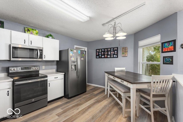 8446 S Paddleboat Ln, Pendleton, IN 46064 - kitchen featuring stainless steel appliances, a textured ceiling, light countertops, white cabinetry, and light wood-type flooring