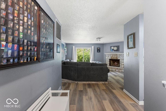 8446 S Paddleboat Ln, Pendleton, IN 46064 - living room with a textured ceiling, wood finished floors, a textured wall, baseboards, and a stone fireplace