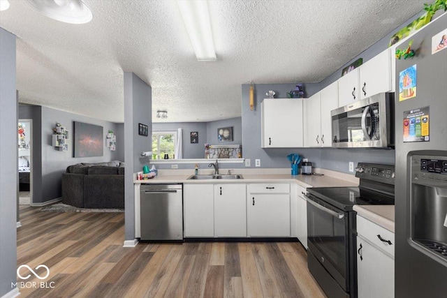 8446 S Paddleboat Ln, Pendleton, IN 46064 - kitchen with stainless steel appliances, a sink, light countertops, wood finished floors, and a textured ceiling