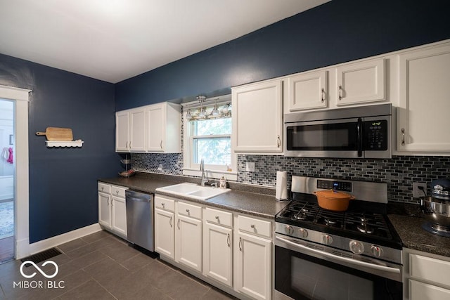 3934 N Kenwood Ave, Indianapolis, IN 46208 - kitchen with stainless steel appliances, a sink, dark countertops, backsplash, and white cabinetry