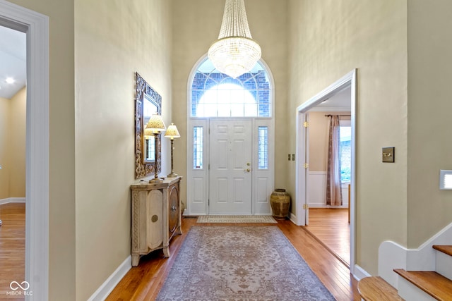 8723 Bergeson Dr, Indianapolis, IN 46278 - foyer featuring a towering ceiling, wood finished floors, a chandelier, stairway, and baseboards