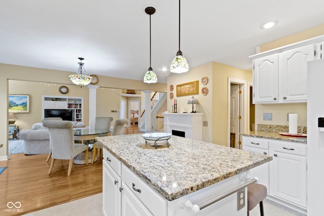 8723 Bergeson Dr, Indianapolis, IN 46278 - kitchen featuring decorative light fixtures, a center island, decorative columns, light wood finished floors, and light stone countertops