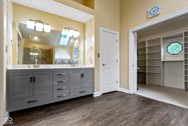 8723 Bergeson Dr, Indianapolis, IN 46278 - bathroom with a shower stall, wood finished floors, double vanity, a skylight, and baseboards