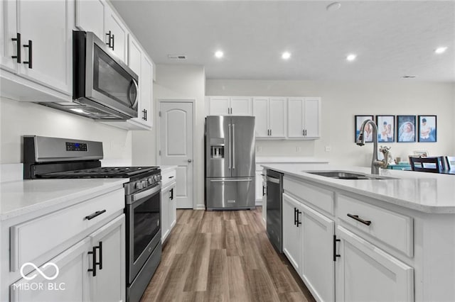 14350 Ludwell Ct, Fishers, IN 46037 - kitchen featuring appliances with stainless steel finishes, a sink, wood finished floors, white cabinetry, and a kitchen island with sink