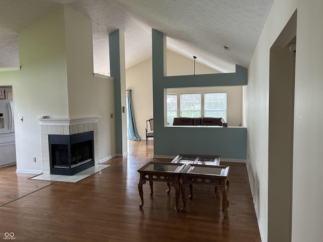 11014 Lake Run Dr, Fishers, IN 46038 - dining space featuring wood finished floors, a textured ceiling, a fireplace, baseboards, and high vaulted ceiling