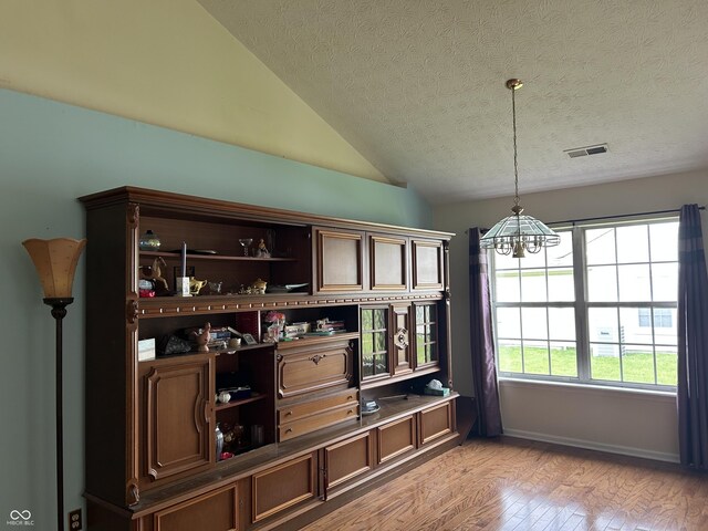 11014 Lake Run Dr, Fishers, IN 46038 - bar area featuring a chandelier, light wood-style flooring, a textured ceiling, vaulted ceiling, and decorative light fixtures