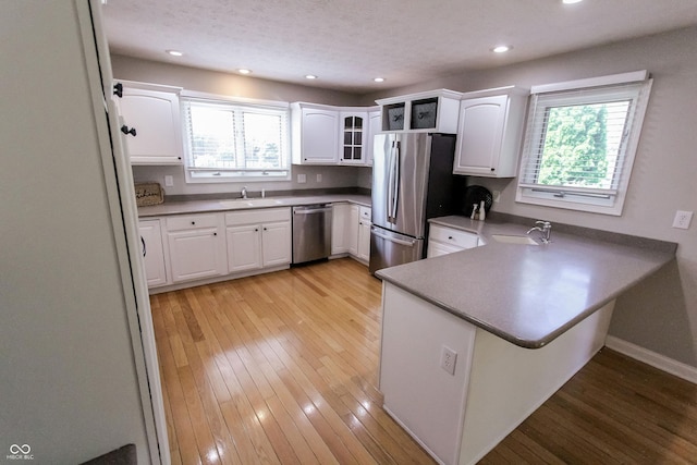 7093 Republic Ln, Indianapolis, IN 46259 - kitchen featuring appliances with stainless steel finishes, a peninsula, white cabinetry, light wood-type flooring, and recessed lighting