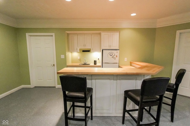 7093 Republic Ln, Indianapolis, IN 46259 - kitchen with freestanding refrigerator, ornamental molding, a breakfast bar, wooden counters, and a sink