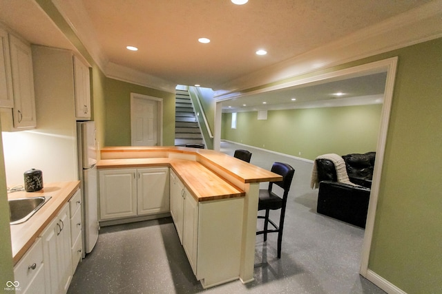 7093 Republic Ln, Indianapolis, IN 46259 - kitchen with wood counters, a sink, a peninsula, freestanding refrigerator, and a breakfast bar area