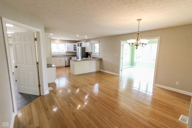 7093 Republic Ln, Indianapolis, IN 46259 - kitchen featuring stainless steel appliances, a chandelier, white cabinetry, baseboards, and a textured ceiling