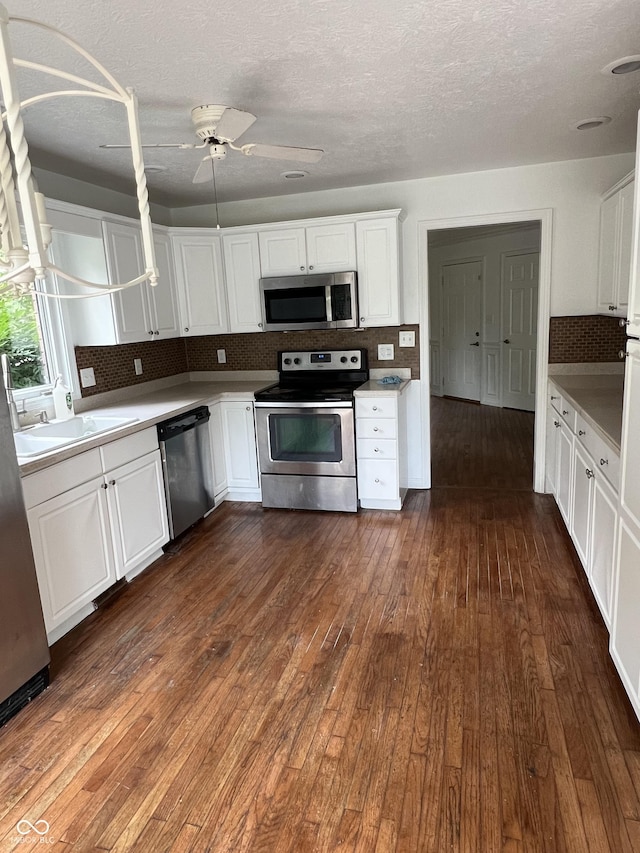 213 Golf Ct, Greenwood, IN 46143 - kitchen featuring appliances with stainless steel finishes, dark wood finished floors, backsplash, white cabinetry, and a ceiling fan
