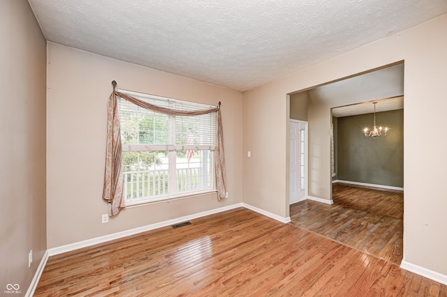1306 Flat Wood Ct, Brownsburg, IN 46112 - unfurnished room with a chandelier, wood finished floors, and a textured ceiling
