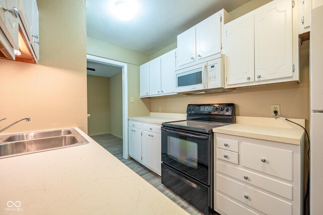 6 Heritage Dr, Terre Haute, IN 47803 - kitchen with white microwave, black range with electric stovetop, a sink, and white cabinetry