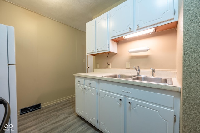 6 Heritage Dr, Terre Haute, IN 47803 - kitchen featuring a sink, dark wood-style flooring, freestanding refrigerator, white cabinets, and light countertops