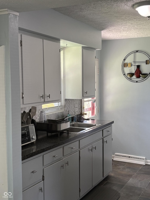 3031 W 18th St, Indianapolis, IN 46222 - kitchen with dark countertops, decorative backsplash, a textured ceiling, a sink, and white cabinets