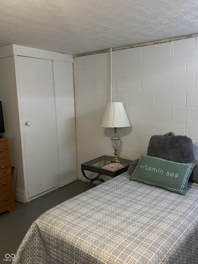 3031 W 18th St, Indianapolis, IN 46222 - bedroom with concrete block wall, finished concrete floors, a closet, and a textured ceiling