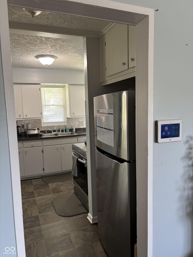 3031 W 18th St, Indianapolis, IN 46222 - kitchen featuring appliances with stainless steel finishes, a sink, dark countertops, decorative backsplash, and white cabinets