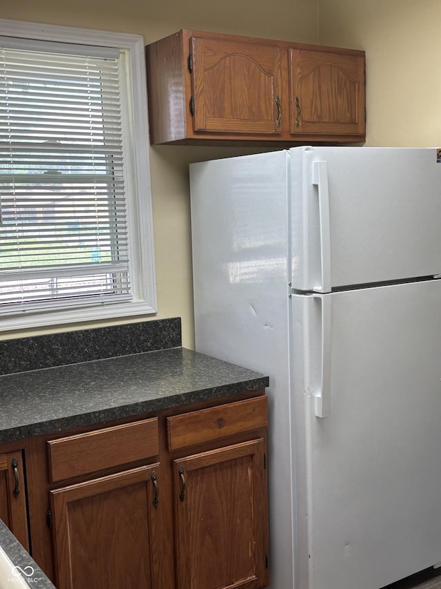 3031 W 18th St, Indianapolis, IN 46222 - kitchen featuring freestanding refrigerator, dark countertops, and brown cabinetry