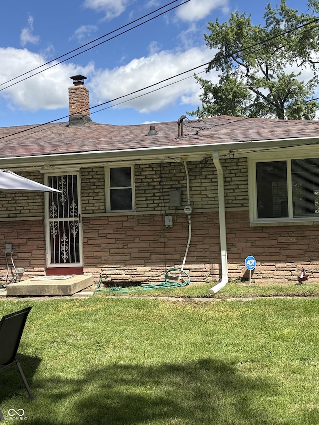 3031 W 18th St, Indianapolis, IN 46222 - back of property with a yard, a chimney, roof with shingles, stone siding, and brick siding