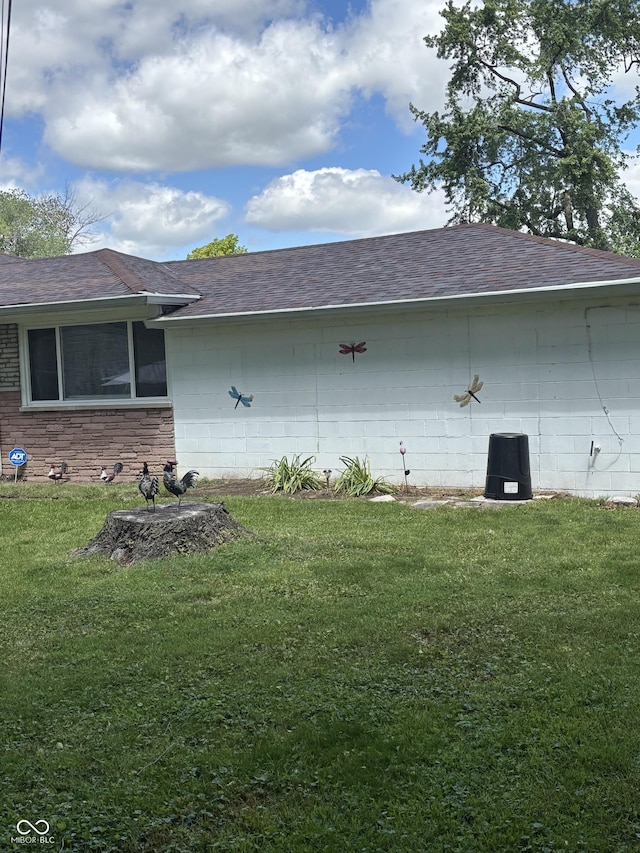 3031 W 18th St, Indianapolis, IN 46222 - view of side of home with concrete block siding, a shingled roof, and a yard