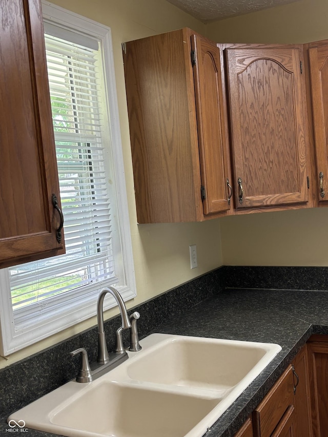3031 W 18th St, Indianapolis, IN 46222 - kitchen with a sink, dark countertops, healthy amount of natural light, and brown cabinetry