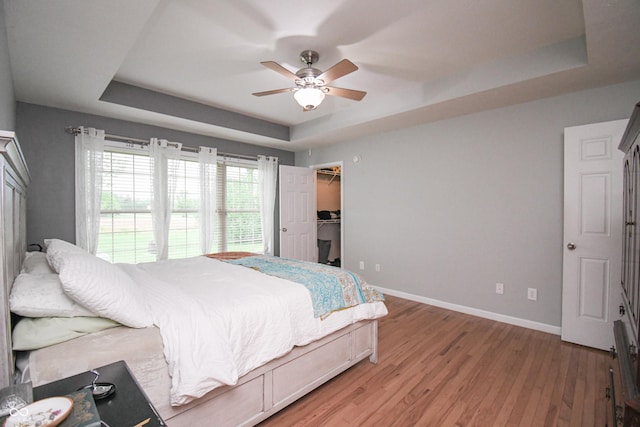 60 Bittersweet Ct, Seymour, IN 47274 - bedroom featuring a raised ceiling, light wood finished floors, baseboards, a ceiling fan, and a walk in closet