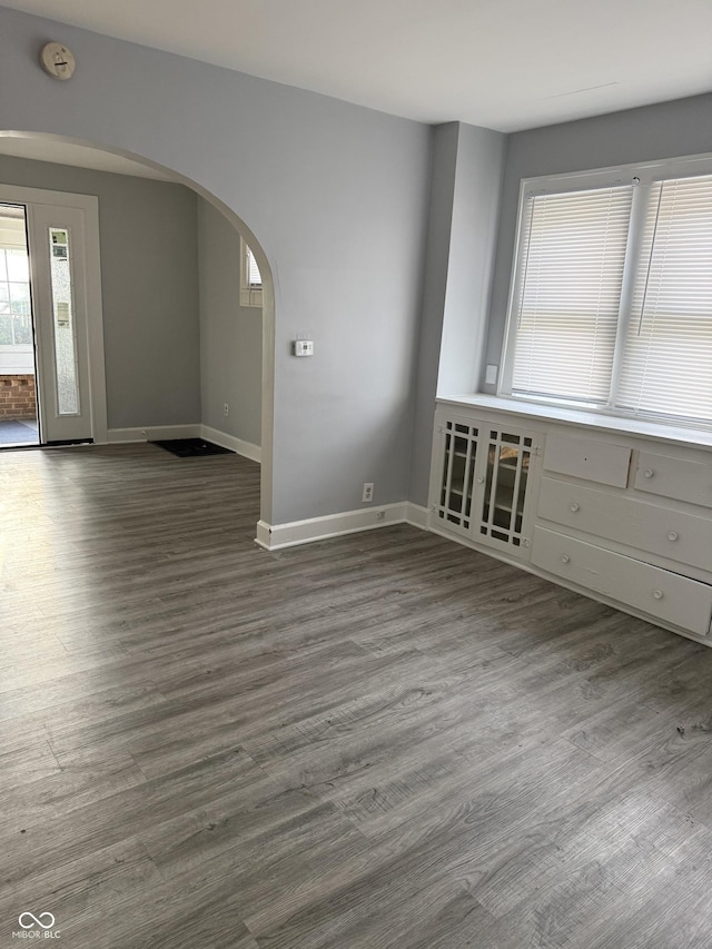 701 N Gladstone Ave, Indianapolis, IN 46201 - unfurnished room featuring arched walkways, baseboards, a smoke detector, and wood finished floors