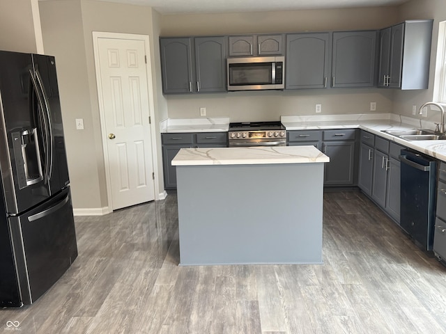 8939 Newchurch Blvd, Indianapolis, IN 46231 - kitchen featuring appliances with stainless steel finishes, a sink, gray cabinets, light stone counters, and wood finished floors