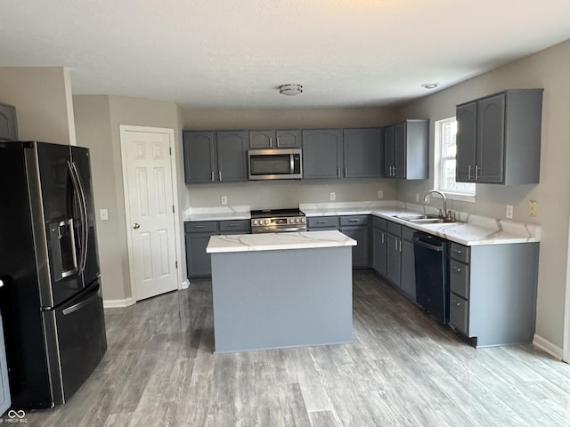 8939 Newchurch Blvd, Indianapolis, IN 46231 - kitchen featuring stainless steel appliances, a sink, gray cabinetry, light wood-style flooring, and a center island