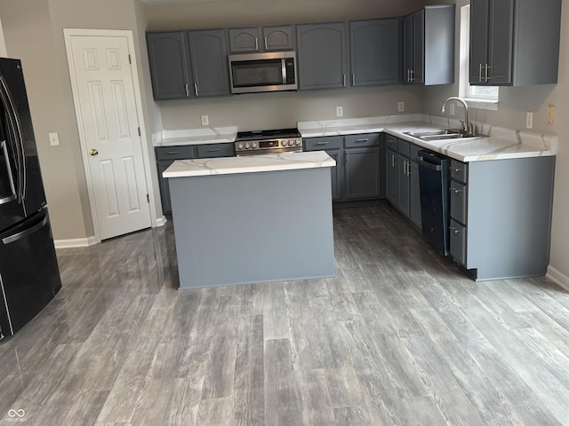 8939 Newchurch Blvd, Indianapolis, IN 46231 - kitchen with stainless steel appliances, a sink, gray cabinets, wood finished floors, and a kitchen island