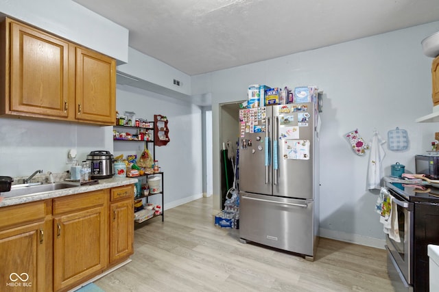 329 S State Ave, Indianapolis, IN 46201 - kitchen featuring appliances with stainless steel finishes, light wood-style floors, a sink, brown cabinetry, and baseboards