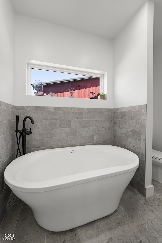 10104 E 850 S, Elizabethtown, IN 47232 - bathroom featuring healthy amount of natural light, tile walls, a soaking tub, toilet, and a wainscoted wall