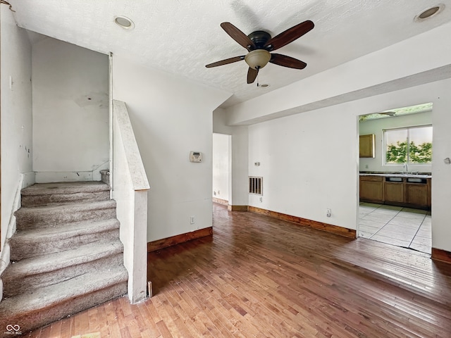 1947 N Parker Ave, Indianapolis, IN 46218 - staircase with ceiling fan, hardwood / wood-style flooring, baseboards, and a textured ceiling
