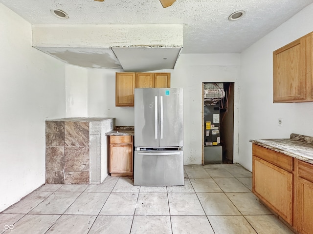 1947 N Parker Ave, Indianapolis, IN 46218 - kitchen with freestanding refrigerator, light tile patterned floors, a textured ceiling, and stone counters