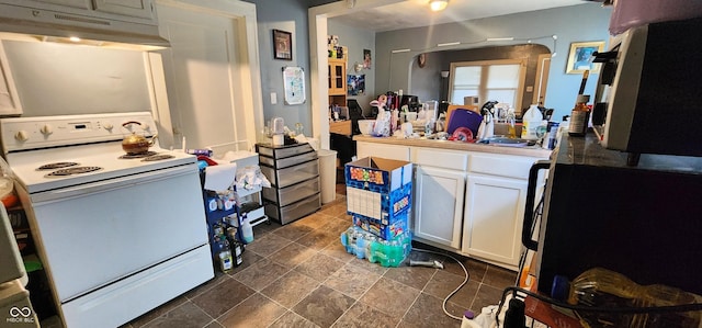 315 S Rural St, Indianapolis, IN 46201 - kitchen featuring white range with electric stovetop, under cabinet range hood, white cabinetry, dark stone finish flooring, and light countertops
