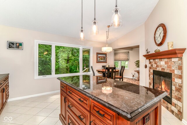 10759 Sawgrass Dr, Fishers, IN 46037 - kitchen with lofted ceiling, light tile patterned floors, brown cabinetry, dark stone countertops, and hanging light fixtures