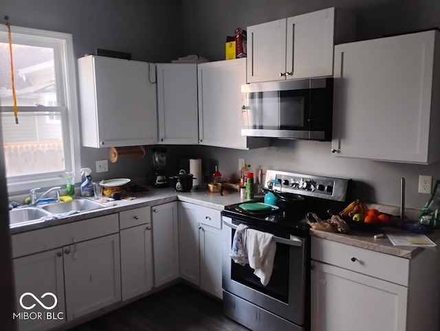 639 N Hamilton Ave, Indianapolis, IN 46201 - kitchen with appliances with stainless steel finishes, a sink, light countertops, white cabinets, and dark wood finished floors