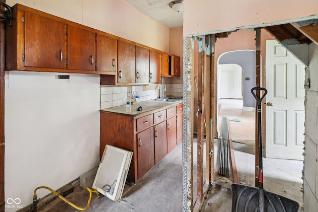 1514 W 2nd St, Marion, IN 46952 - kitchen with a sink, brown cabinets, concrete flooring, tasteful backsplash, and arched walkways