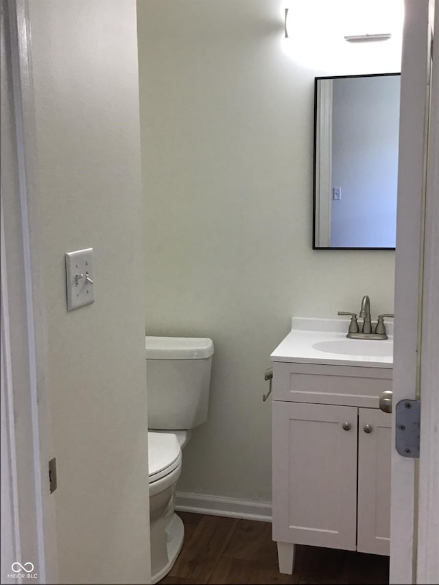 6070 Southbay Dr, Indianapolis, IN 46250 - half bathroom with vanity, baseboards, toilet, and wood finished floors