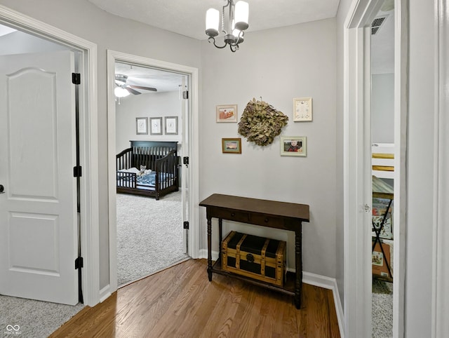 319 Mcintosh Ln, Westfield, IN 46074 - hallway featuring wood finished floors, a chandelier, baseboards, and an upstairs landing