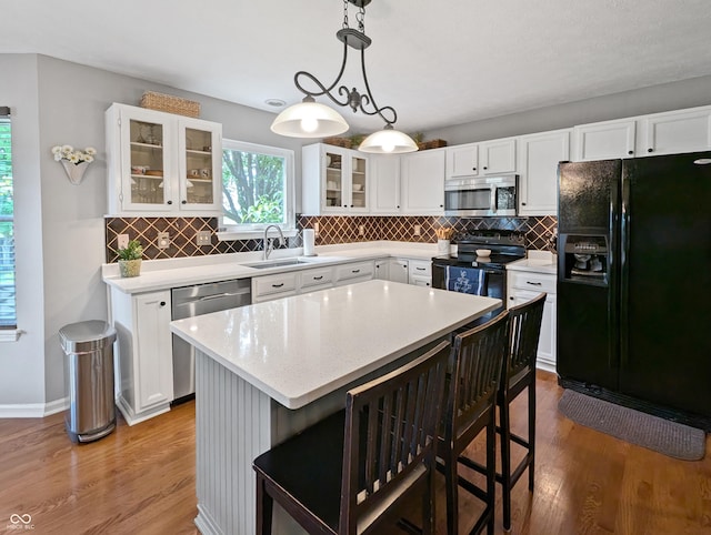 319 Mcintosh Ln, Westfield, IN 46074 - kitchen featuring black appliances, a sink, wood finished floors, and a kitchen bar