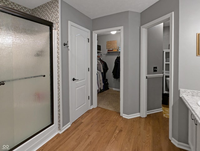 319 Mcintosh Ln, Westfield, IN 46074 - bathroom with a stall shower, wood finished floors, vanity, a spacious closet, and baseboards