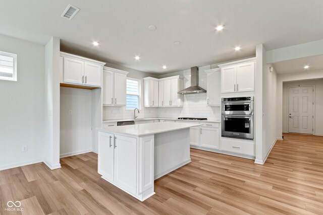 7248 Covington St, Lebanon, IN 46052 - kitchen featuring wall chimney range hood, appliances with stainless steel finishes, a center island, tasteful backsplash, and white cabinetry