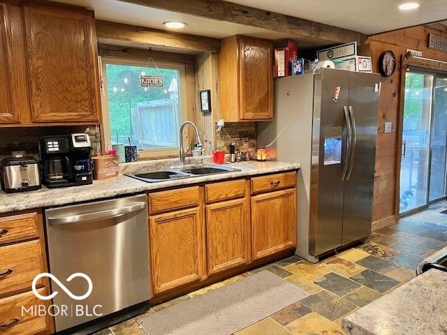 6774 S Becks Grove Rd, Freetown, IN 47235 - kitchen featuring appliances with stainless steel finishes, stone tile floors, a sink, brown cabinetry, and light countertops