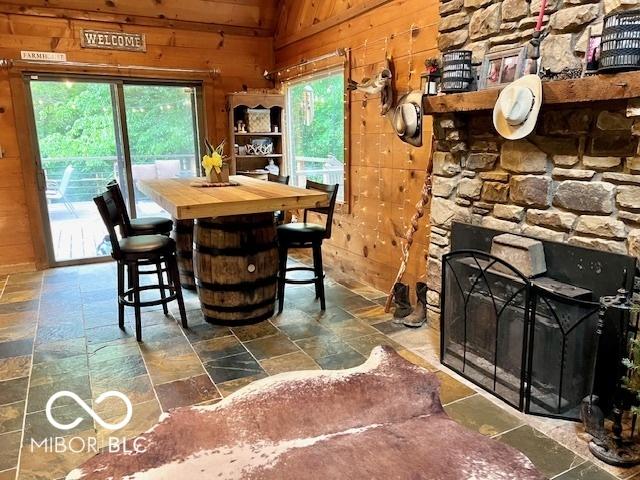 6774 S Becks Grove Rd, Freetown, IN 47235 - dining area featuring stone tile flooring, wood walls, and plenty of natural light