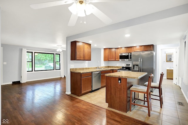 3126 Carriage Rd, West Lafayette, IN 47906 - kitchen with appliances with stainless steel finishes, ceiling fan, a sink, a center island, and light wood-style flooring