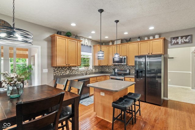 9756 Brook Meadow Dr, Mccordsville, IN 46055 - kitchen featuring stainless steel appliances, light wood-style flooring, tasteful backsplash, a center island, and hanging light fixtures