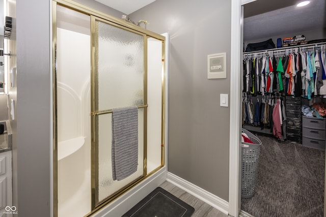 28 Patriot Ct, Greenfield, IN 46140 - bathroom with a stall shower, baseboards, a walk in closet, and wood finished floors