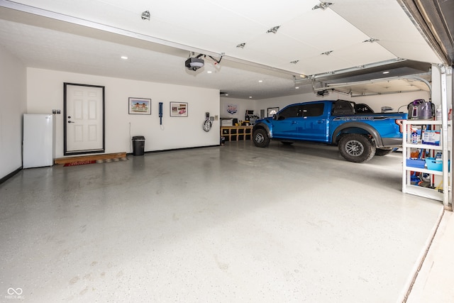 28 Patriot Ct, Greenfield, IN 46140 - garage featuring a garage door opener and fridge